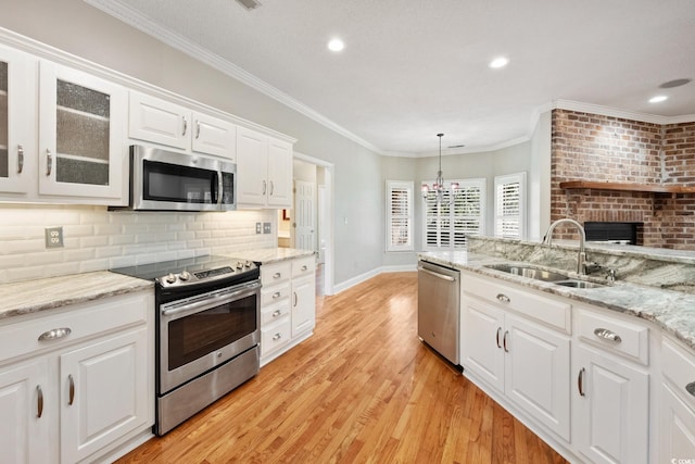 kitchen featuring stainless steel appliances, hanging light fixtures, sink, white cabinetry, and backsplash