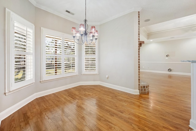 unfurnished dining area featuring an inviting chandelier, hardwood / wood-style floors, and crown molding