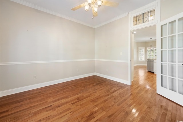 spare room with ceiling fan with notable chandelier, hardwood / wood-style flooring, and crown molding