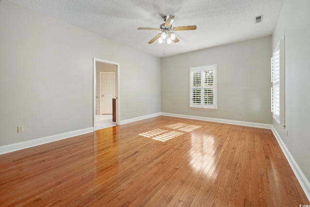 empty room with a textured ceiling, ceiling fan, and light hardwood / wood-style floors