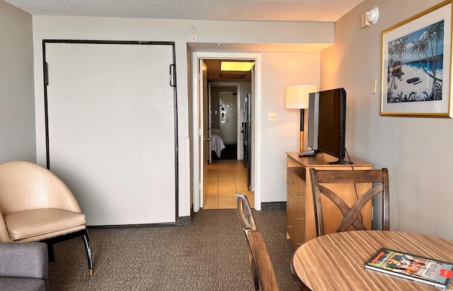 interior space featuring a textured ceiling and dark colored carpet