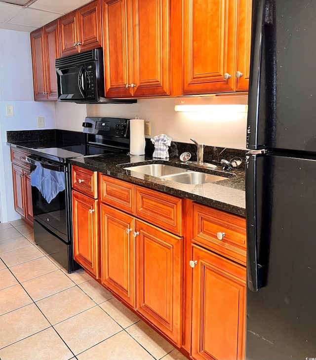 kitchen featuring dark stone countertops, sink, light tile patterned floors, and black appliances