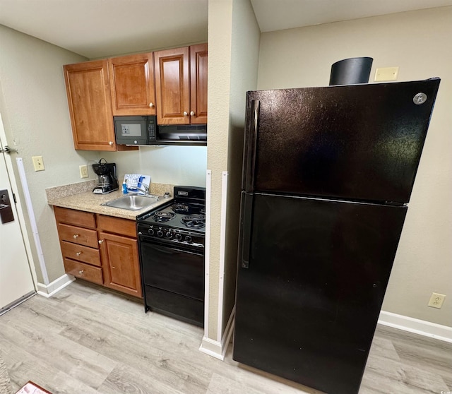 kitchen featuring sink, light hardwood / wood-style flooring, and black appliances