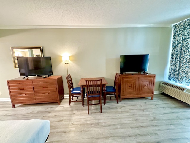 living room featuring crown molding, a wall unit AC, a textured ceiling, and light hardwood / wood-style flooring