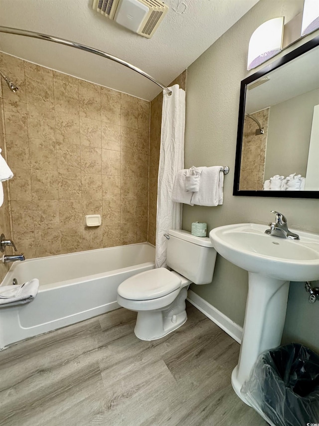 bathroom with shower / bath combo, wood-type flooring, toilet, and a textured ceiling