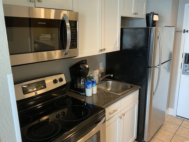 6900 N Ocean Blvd Unit 614, Myrtle Beach, SC 29572 - kitchen with stainless steel appliances, a sink, white cabinets, light tile patterned floors, and dark stone countertops