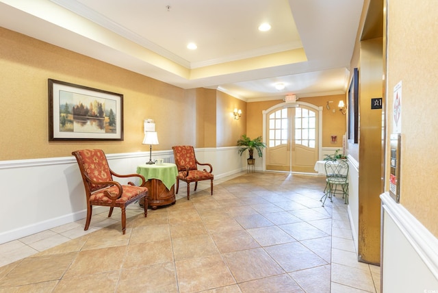 sitting room with french doors, a raised ceiling, ornamental molding, and light tile patterned floors