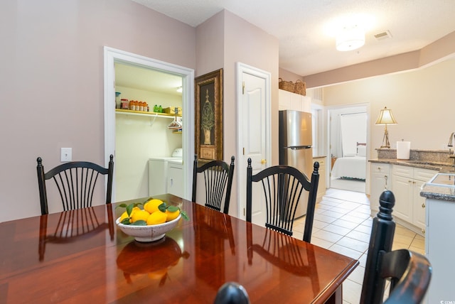 tiled dining space featuring washing machine and clothes dryer and sink