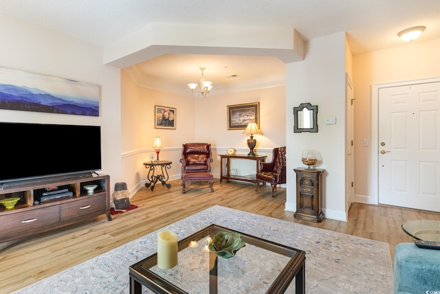 living room with a textured ceiling, crown molding, a chandelier, and hardwood / wood-style floors