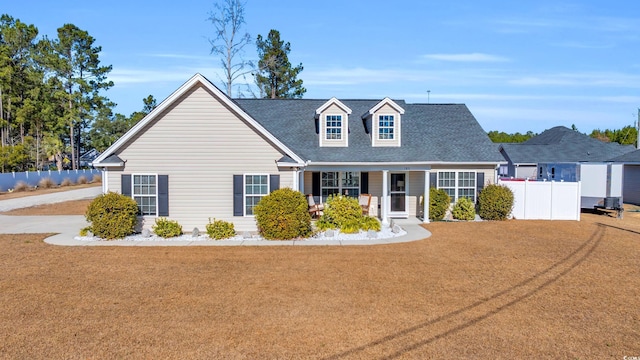 cape cod house featuring covered porch and a front yard