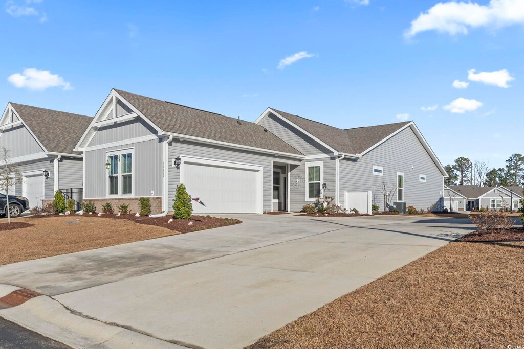 4040 Taranto Loop Unit D, Myrtle Beach, SC 29579 - view of front facade with a shingled roof, a garage, concrete driveway, and board and batten siding