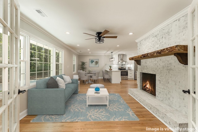 106 Governor Boone Ln, Georgetown, SC 29440 - living area featuring crown molding, light wood-style floors, a fireplace, a ceiling fan, and visible vents