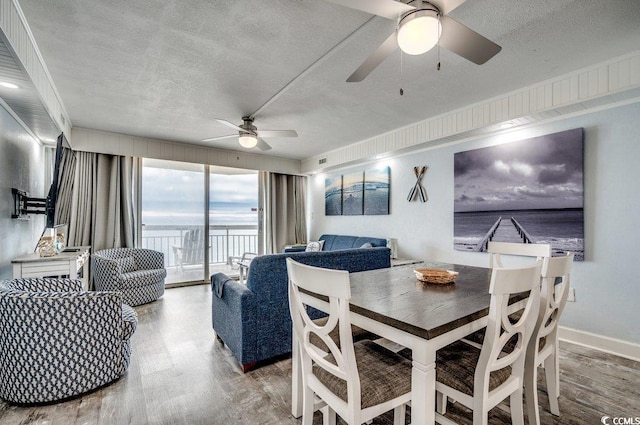 dining space featuring baseboards, a ceiling fan, wood finished floors, and a textured ceiling