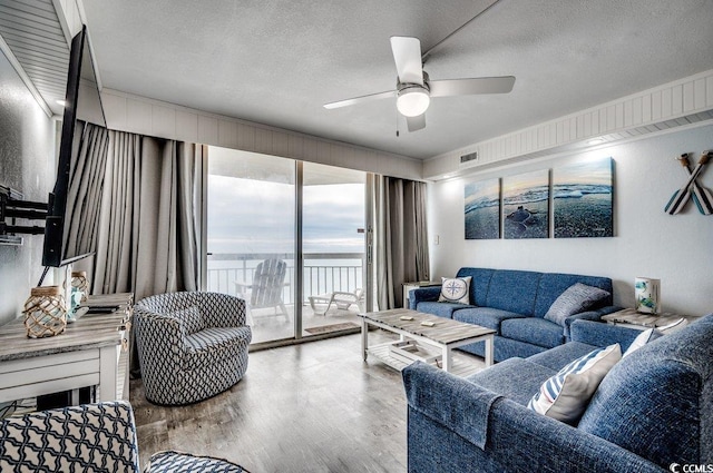 living room with a ceiling fan, visible vents, wood finished floors, and a textured ceiling