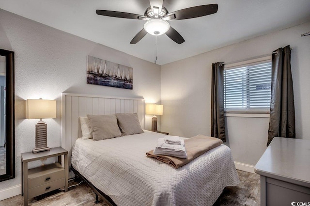 bedroom with wood finished floors, a ceiling fan, and baseboards