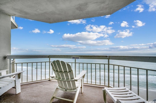 balcony with a water view and a view of the beach