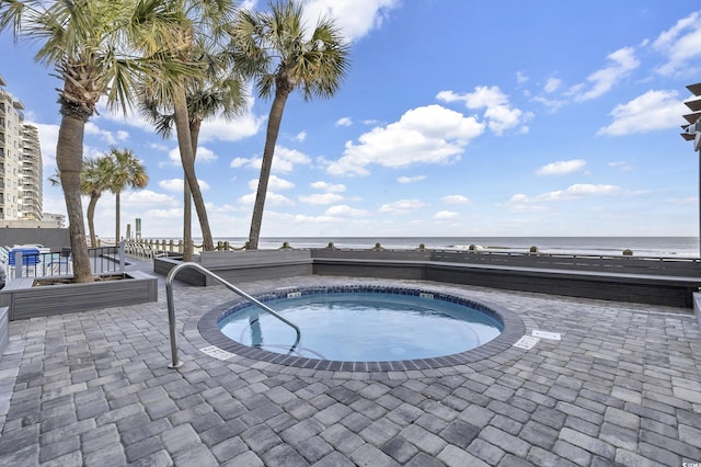 view of pool featuring a community hot tub, a water view, and a patio area