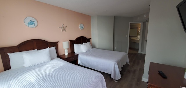 bedroom with connected bathroom and dark hardwood / wood-style floors