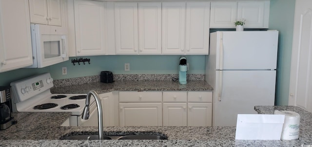 kitchen with sink, white appliances, white cabinets, and stone countertops