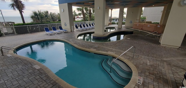 view of swimming pool with a patio and a water view