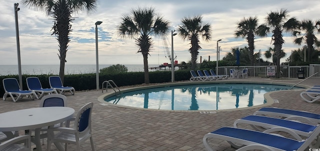 view of swimming pool featuring a water view and a patio area