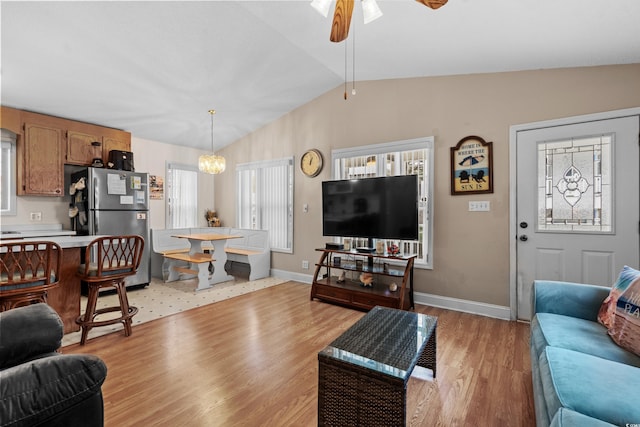 living room featuring light hardwood / wood-style floors, lofted ceiling, and ceiling fan with notable chandelier