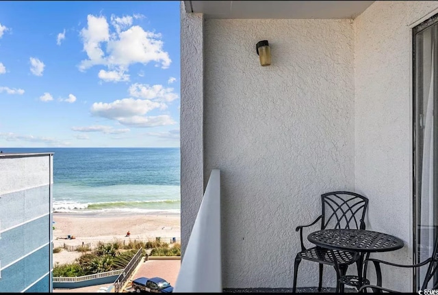 balcony featuring a view of the beach and a water view