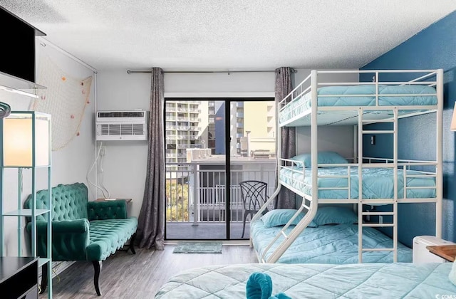 bedroom featuring an AC wall unit, a textured ceiling, and hardwood / wood-style flooring