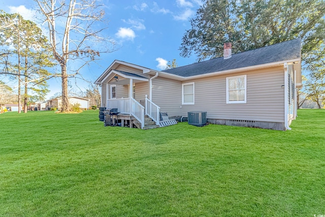 rear view of house featuring central AC and a yard