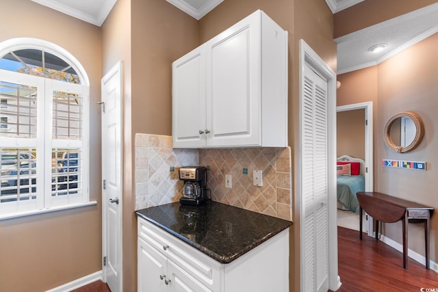 kitchen with crown molding, dark stone counters, dark hardwood / wood-style flooring, decorative backsplash, and white cabinets