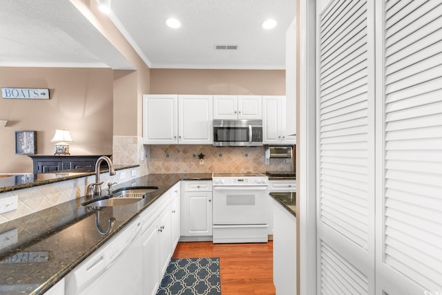 kitchen featuring sink, white cabinetry, white appliances, decorative backsplash, and dark stone counters