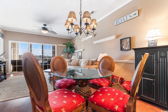 dining space featuring ceiling fan with notable chandelier, ornamental molding, and wood-type flooring