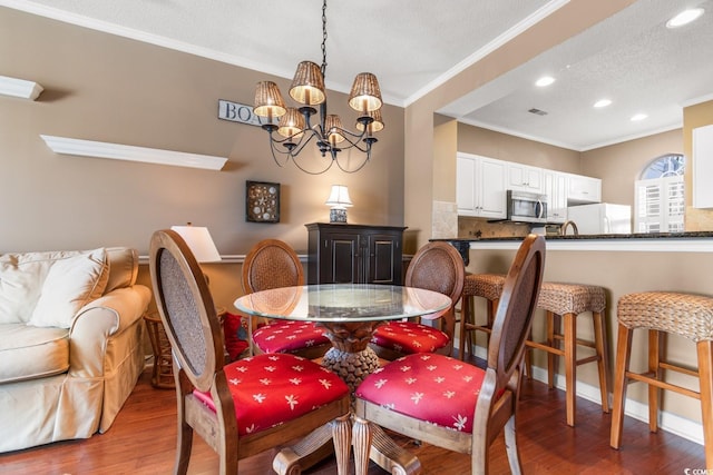 dining space with a notable chandelier, crown molding, a textured ceiling, and hardwood / wood-style flooring