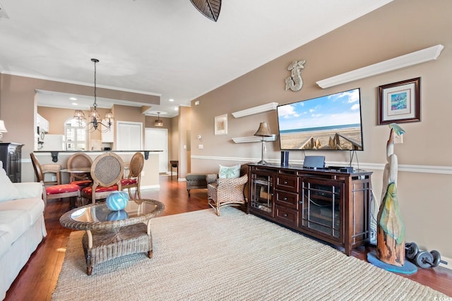 living room with ornamental molding, an inviting chandelier, and wood-type flooring