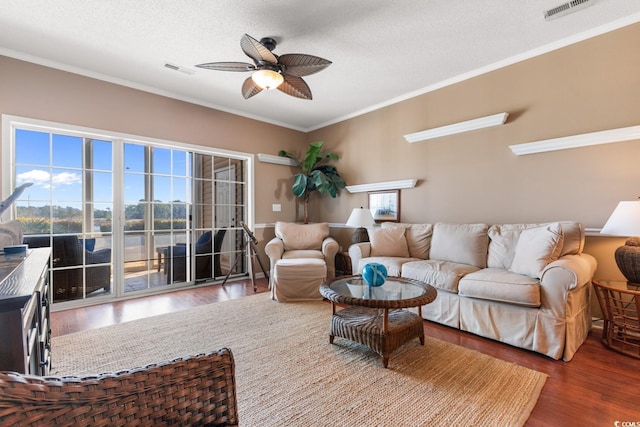 living room with a textured ceiling, ceiling fan, crown molding, and wood-type flooring