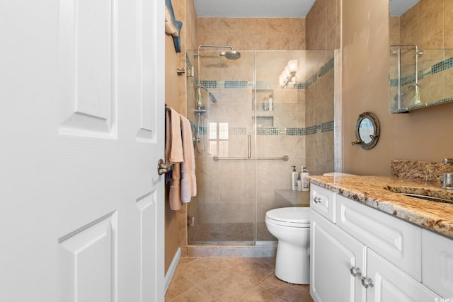 bathroom featuring toilet, a shower with door, vanity, and tile patterned floors