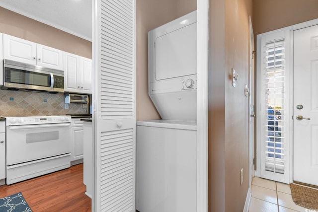 laundry room featuring stacked washer / dryer and light tile patterned flooring