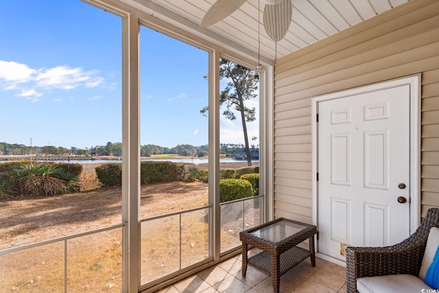 sunroom / solarium featuring ceiling fan and a water view