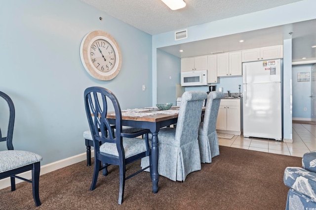 tiled dining room featuring a textured ceiling