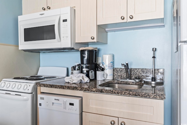 kitchen with sink, dark stone countertops, and white appliances