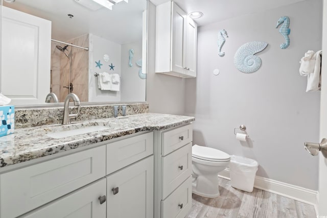 bathroom featuring a shower, hardwood / wood-style floors, toilet, and vanity