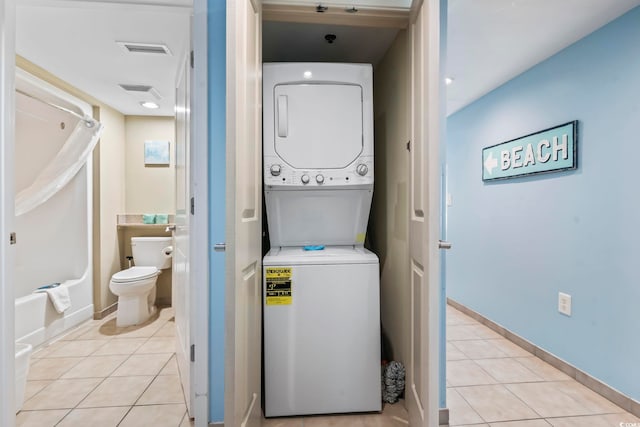 washroom with light tile patterned floors and stacked washer / dryer