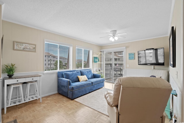 living room with ceiling fan, ornamental molding, a textured ceiling, and light parquet floors