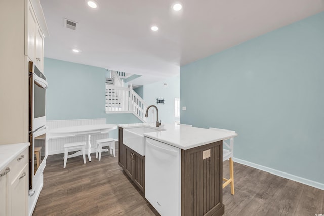 kitchen with dishwasher, dark hardwood / wood-style floors, sink, white cabinetry, and an island with sink