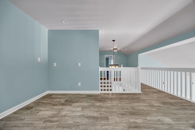 spare room featuring hardwood / wood-style flooring, lofted ceiling, and a chandelier