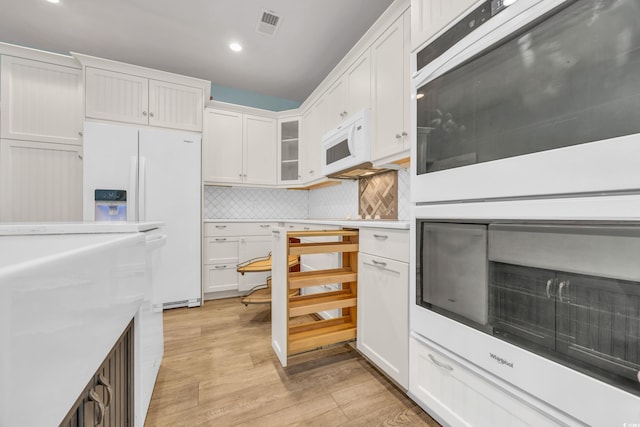 kitchen featuring backsplash, white appliances, white cabinetry, and light hardwood / wood-style floors