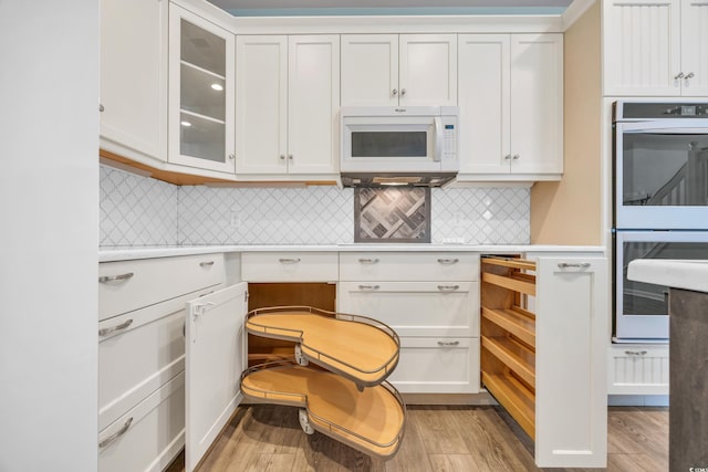 kitchen featuring white cabinets, double wall oven, and tasteful backsplash