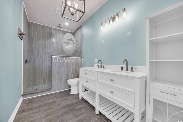 bathroom with toilet, a tile shower, hardwood / wood-style floors, and vanity