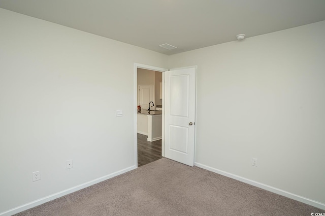 unfurnished room with sink and dark carpet