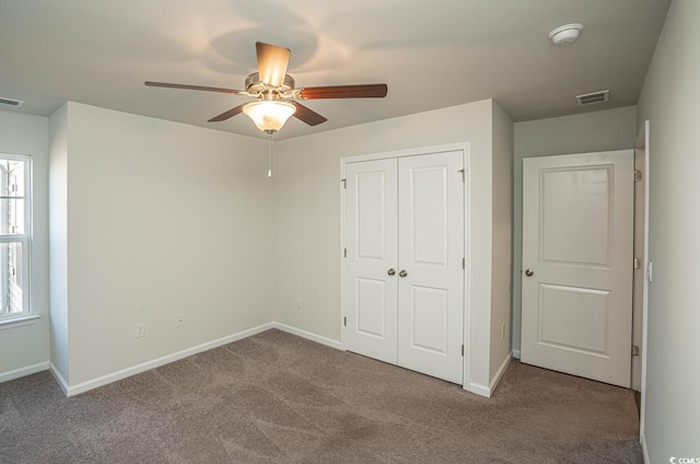 unfurnished bedroom with ceiling fan, multiple windows, a closet, and carpet